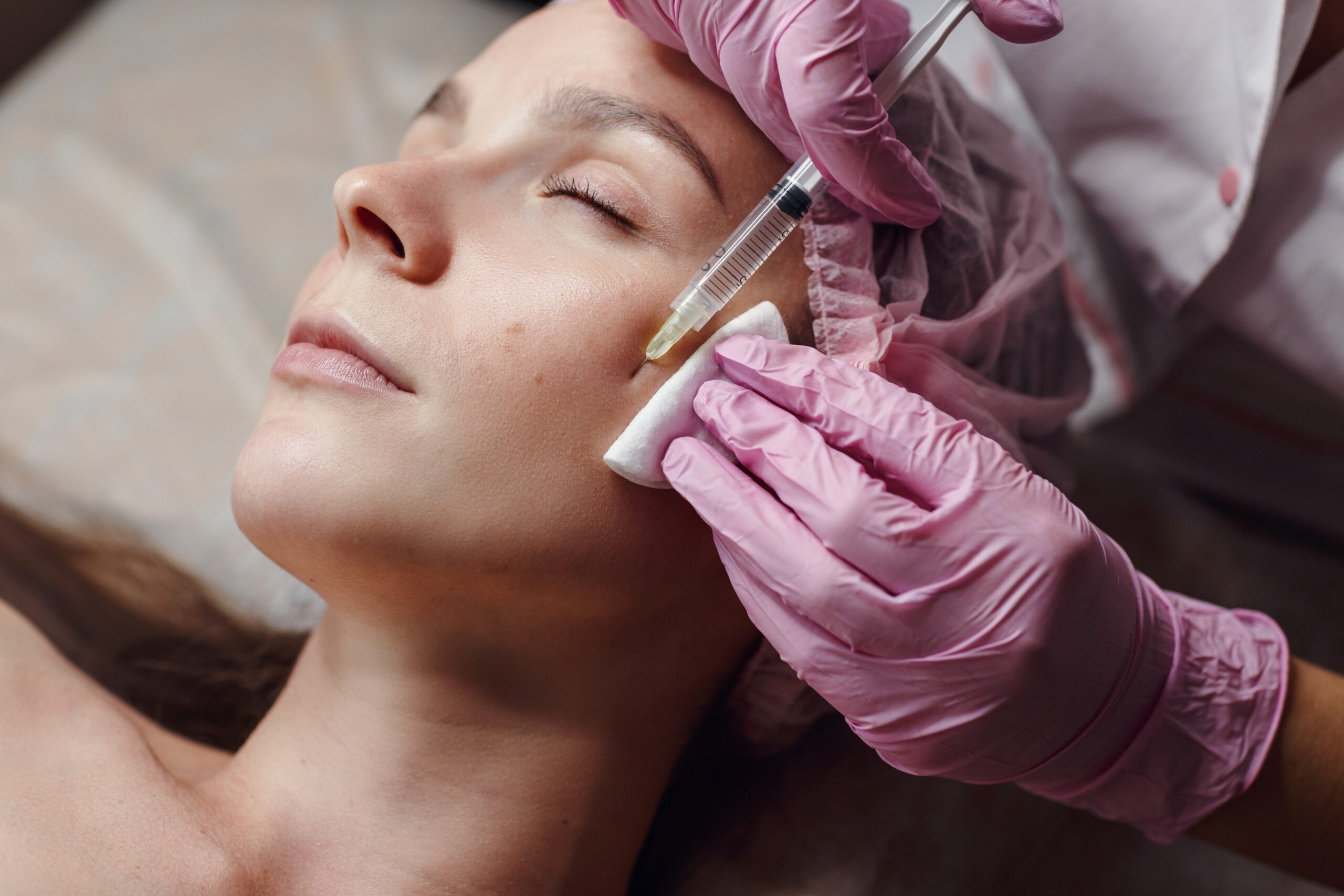 Aesthetic practitioner injecting cheek filler in a clinic setting