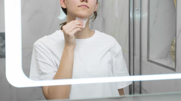 Woman using smart mirror for AI skin scan.