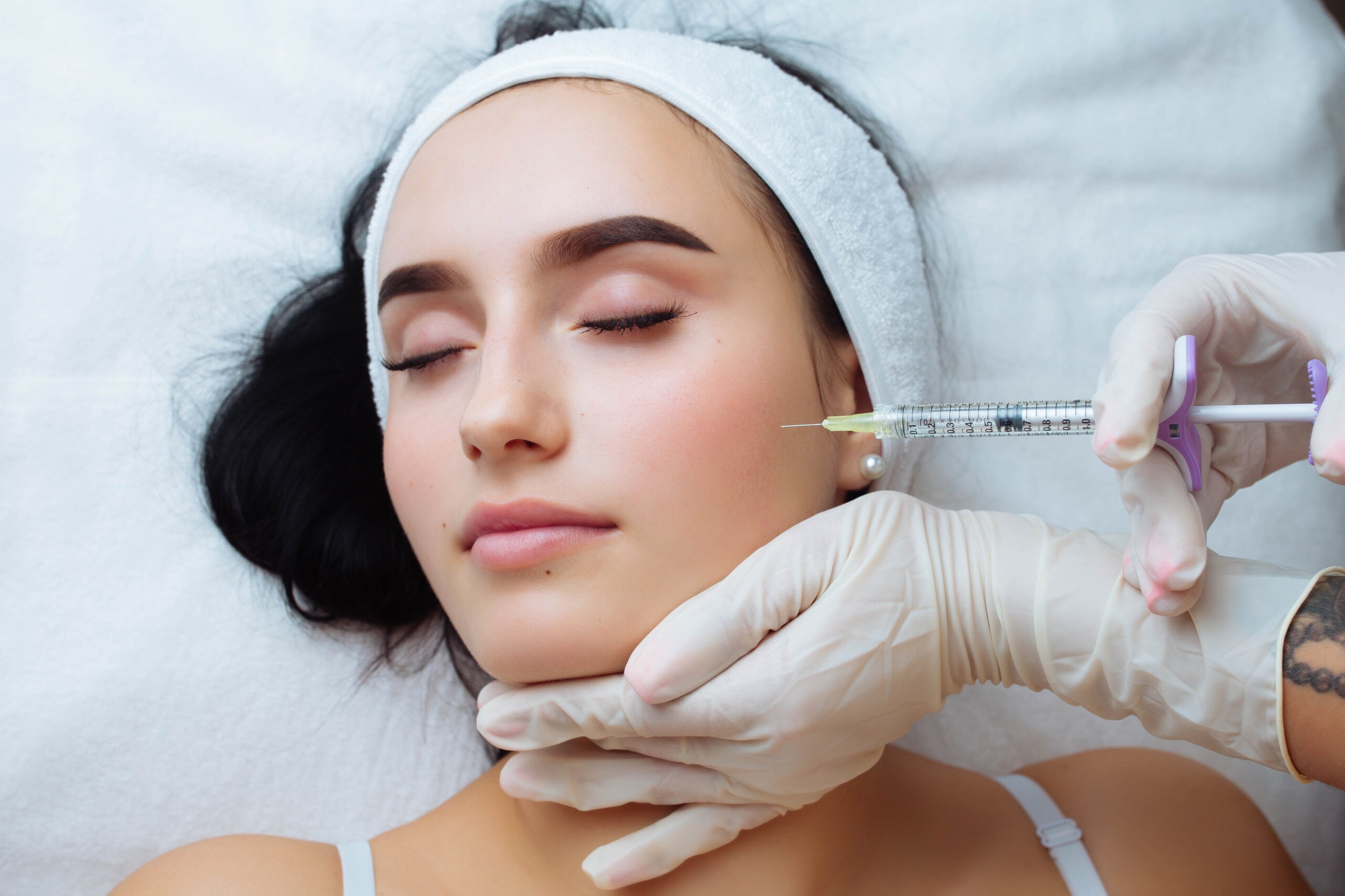 Aesthetic specialist injecting cheek filler in clinic